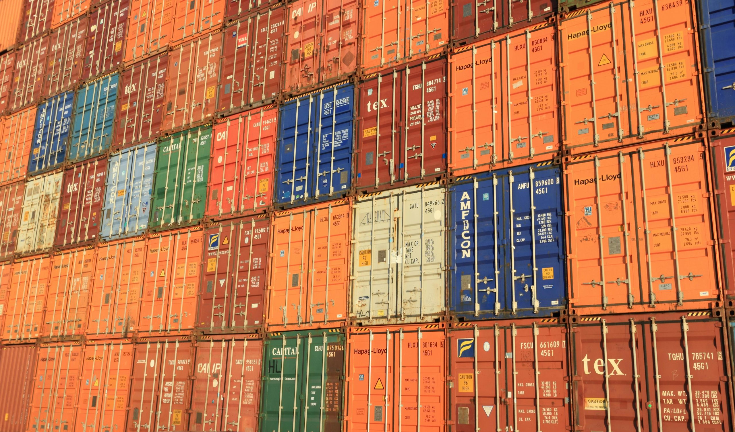 Colorful shipping containers stacked in a harbor, symbolizing global trade.