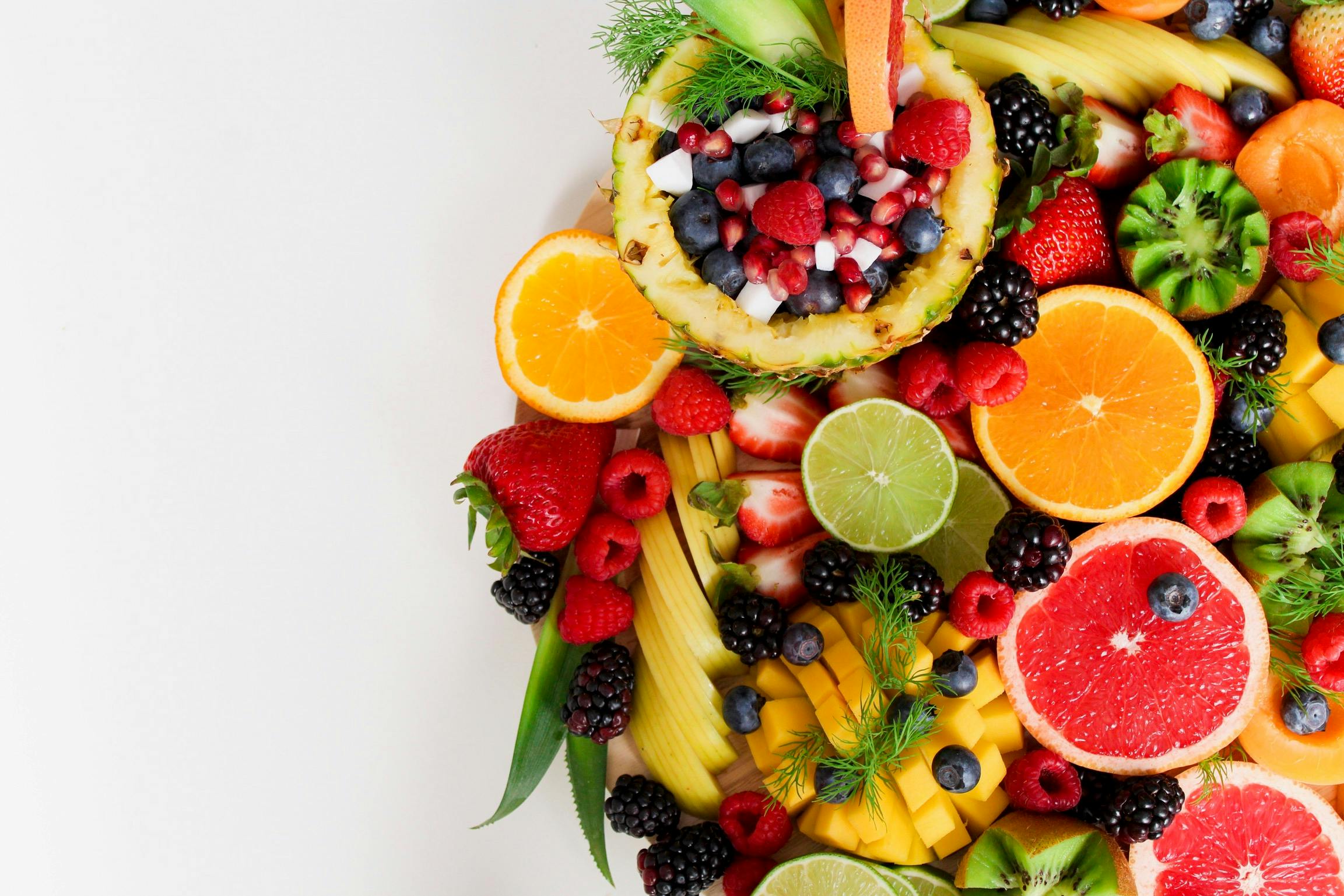 Colorful flat lay of assorted tropical fruits including pineapple, berries, and citrus.