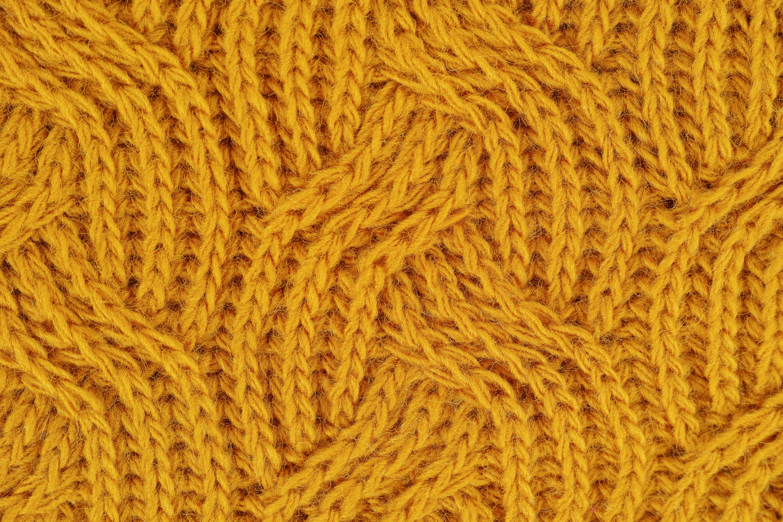 Detailed close-up of a yellow knitted wool pattern, ideal for textile design.