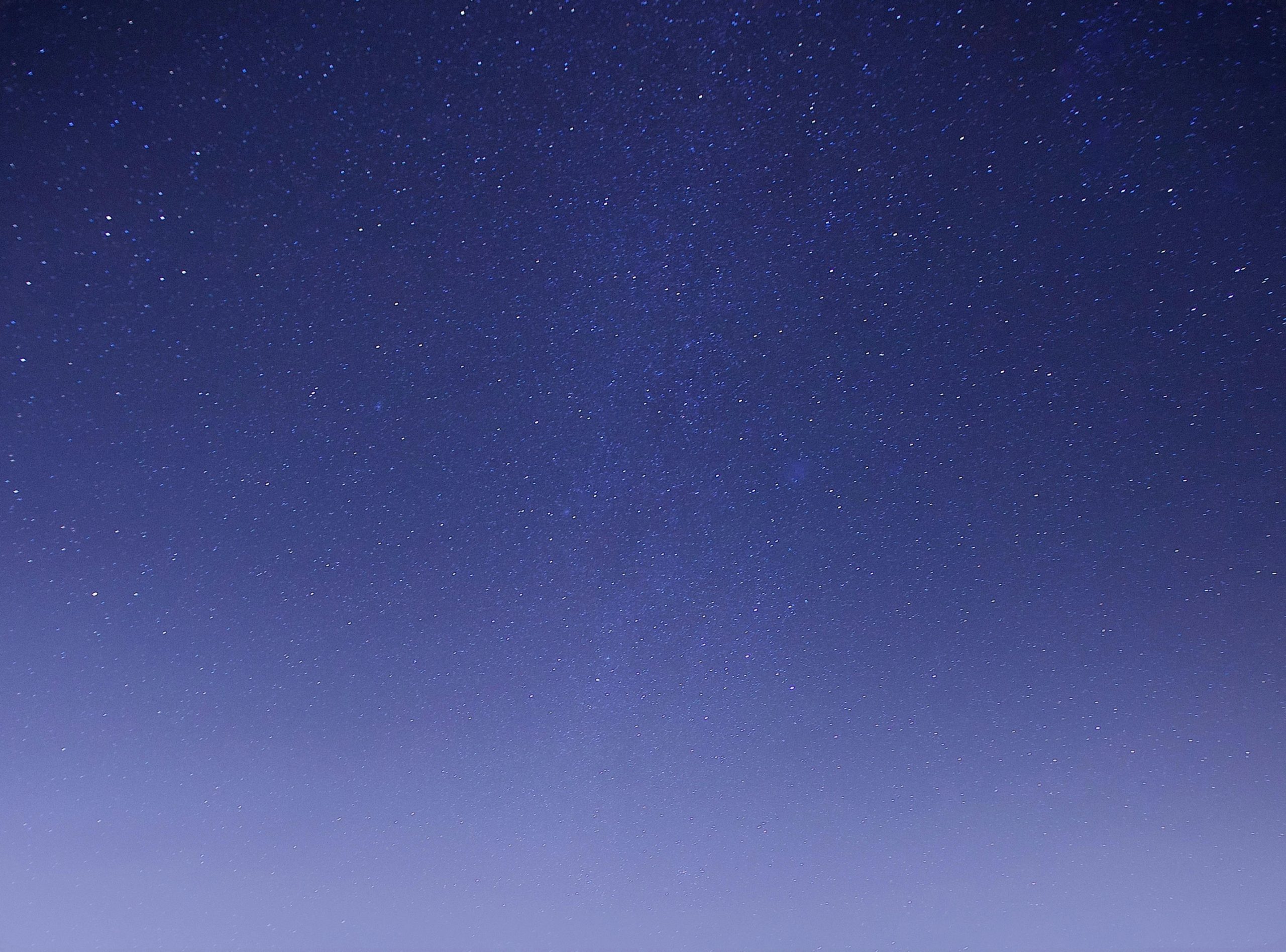A beautiful view of the night sky filled with twinkling stars under a clear, dark blue atmosphere.