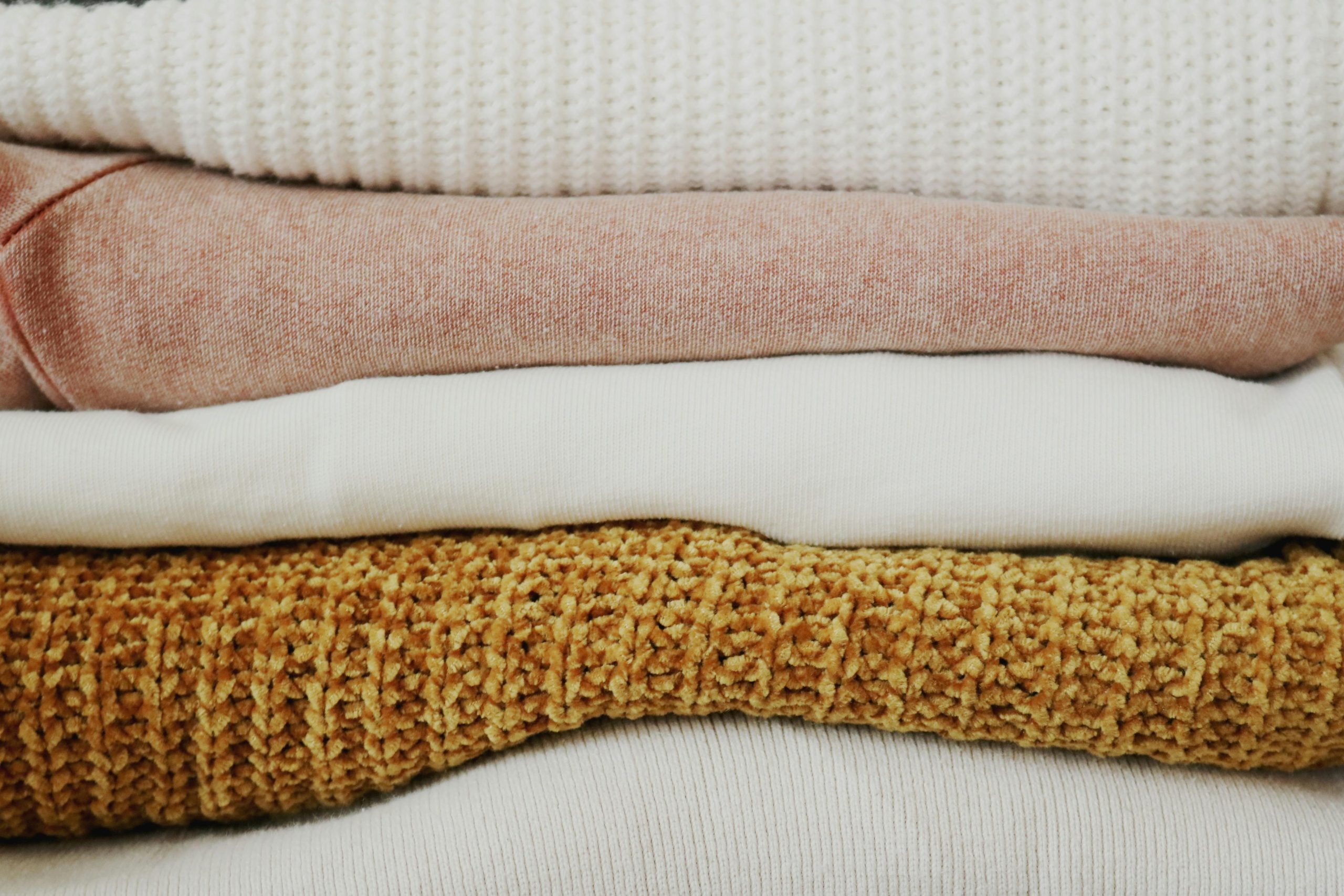 A close-up view of neatly stacked, warm fabrics showcasing various textures and colors.