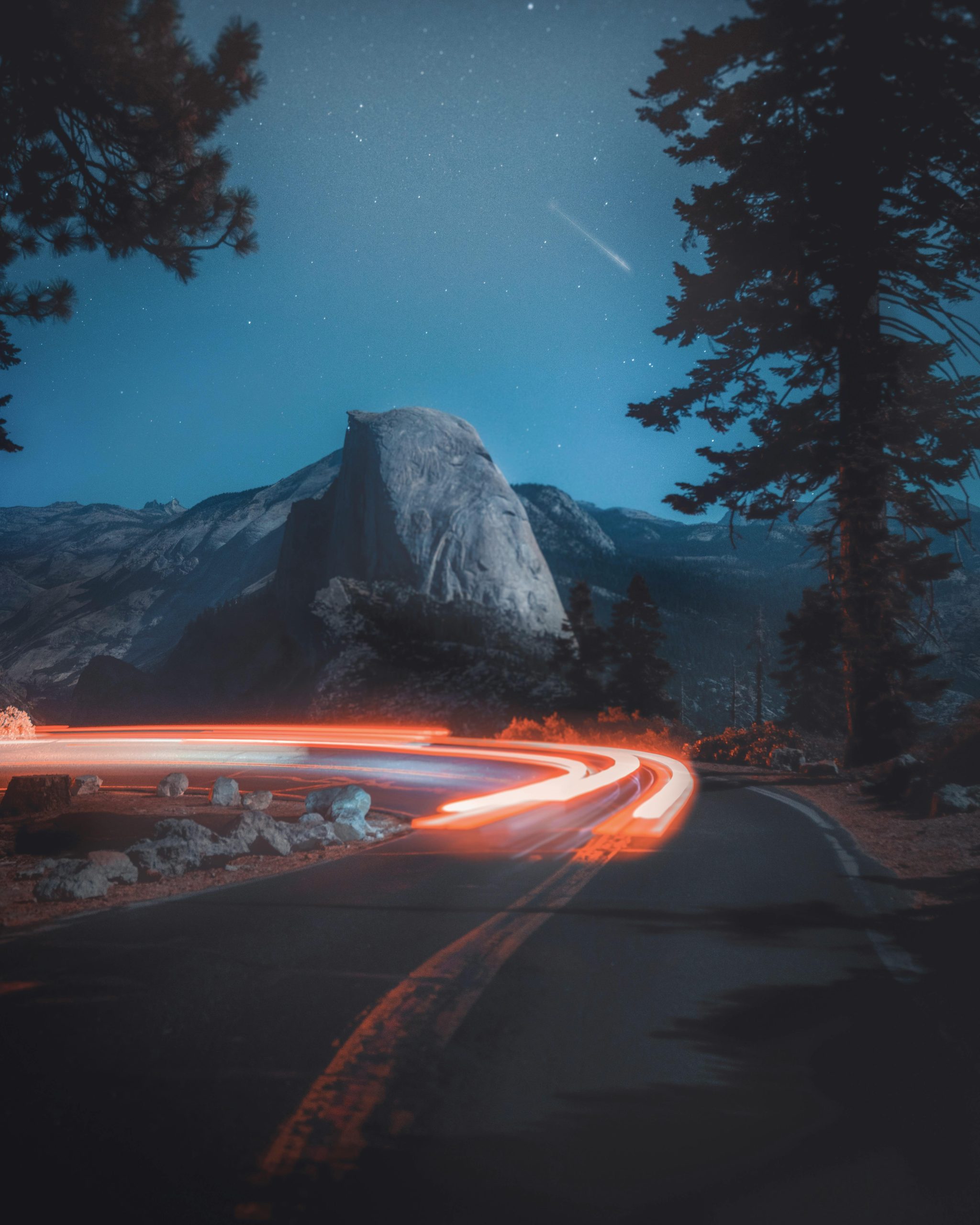 Breathtaking long exposure of light trails on a road under the starry night sky in Yosemite.
