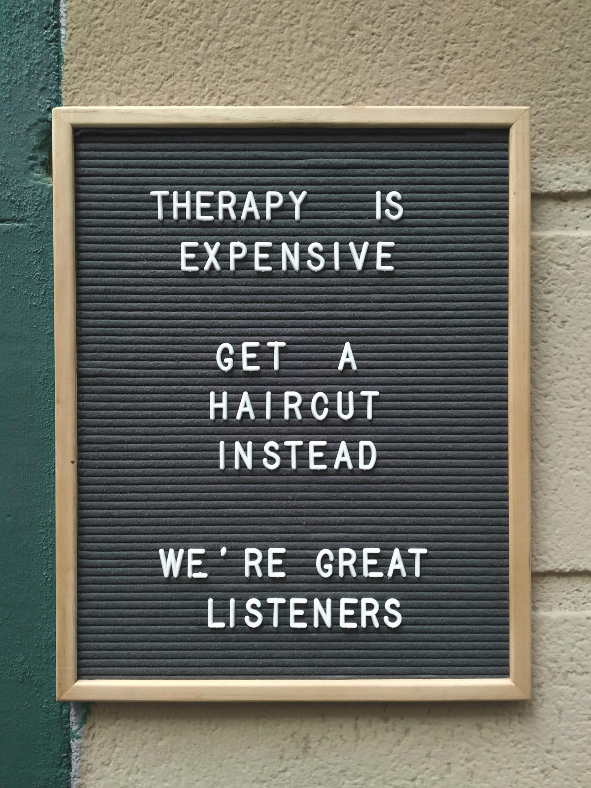 Funny hair salon sign suggesting haircuts over therapy for listening.