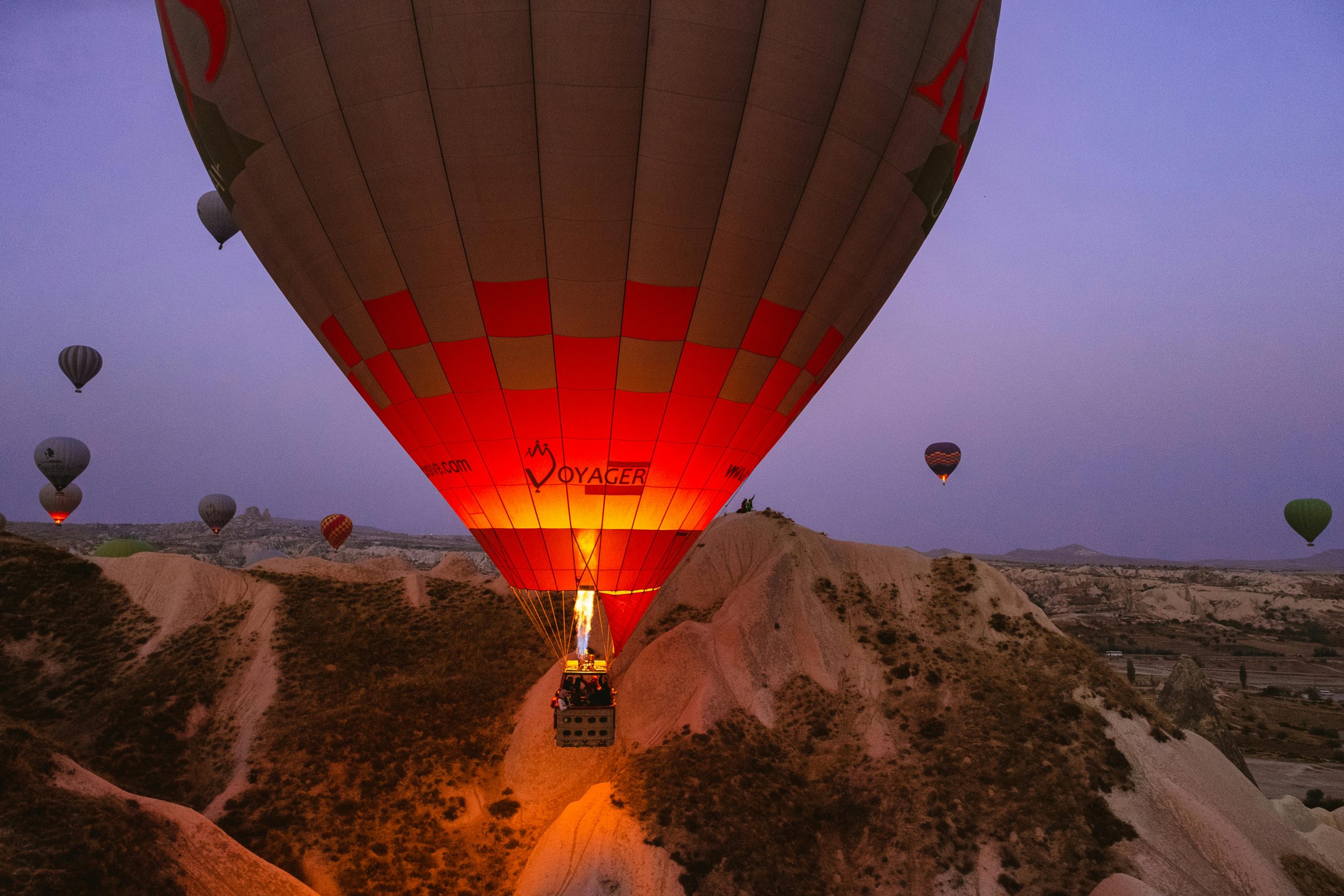 Breathtaking view of hot air balloons soaring over the rocky landscape of Cappadocia, Turkey at sunrise.