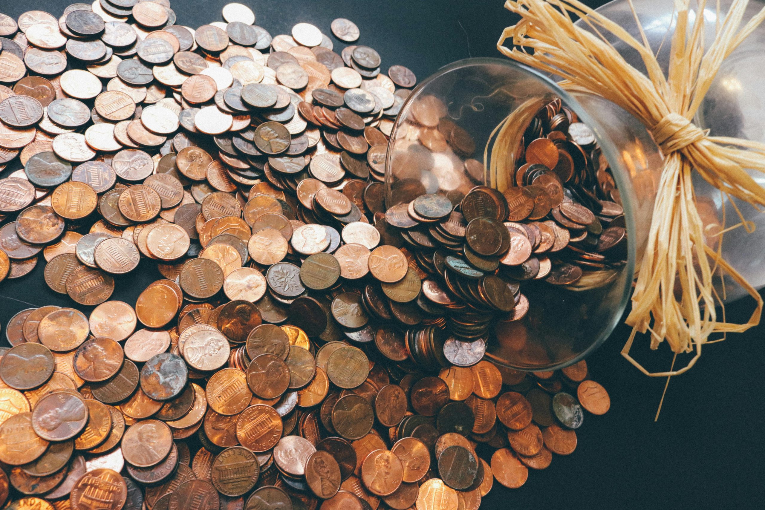 Spilled jar of pennies creating a pattern of coins representing savings and finance.