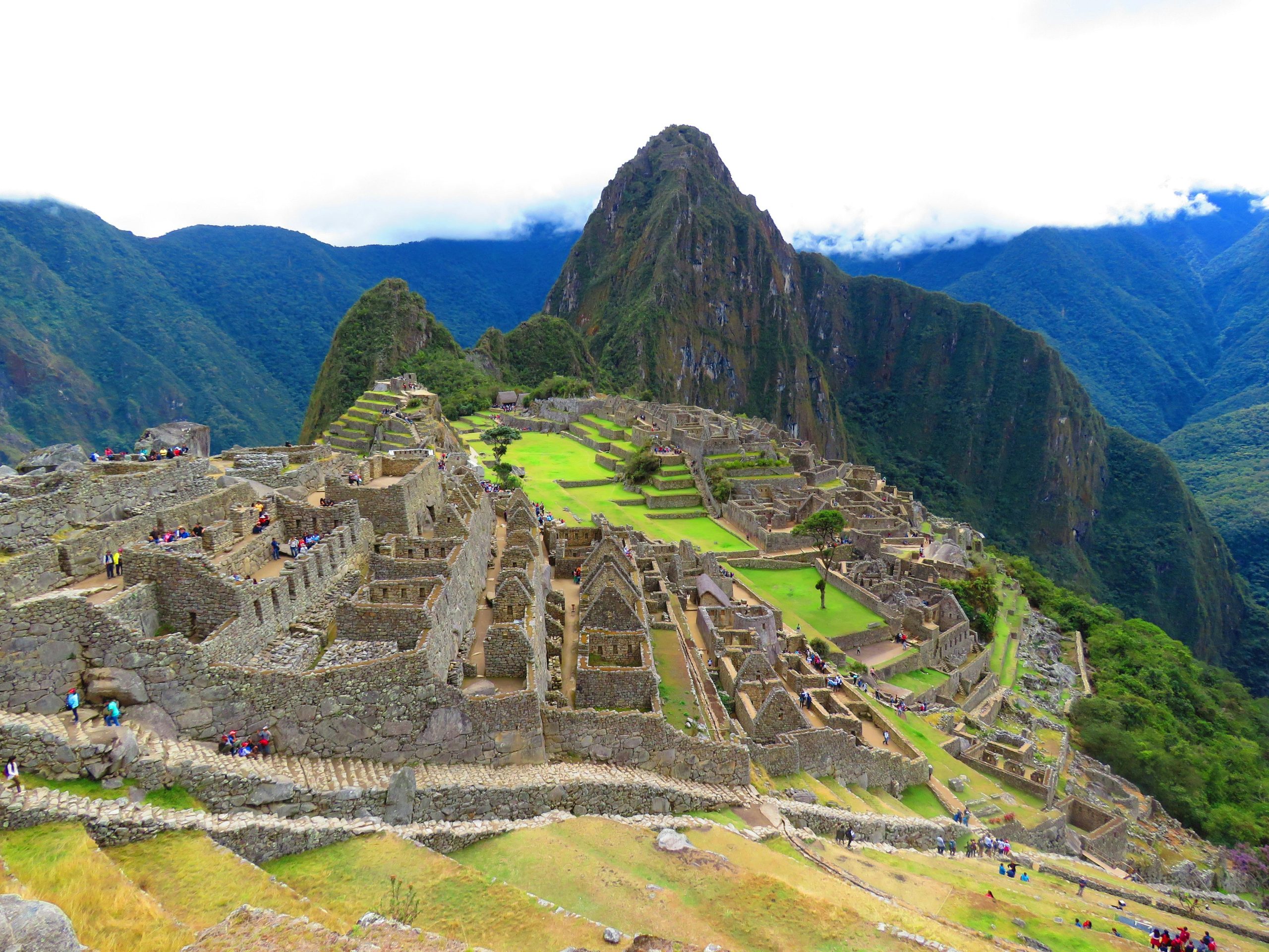 Stunning aerial perspective of Machu Picchu with lush surroundings under a cloudy sky.