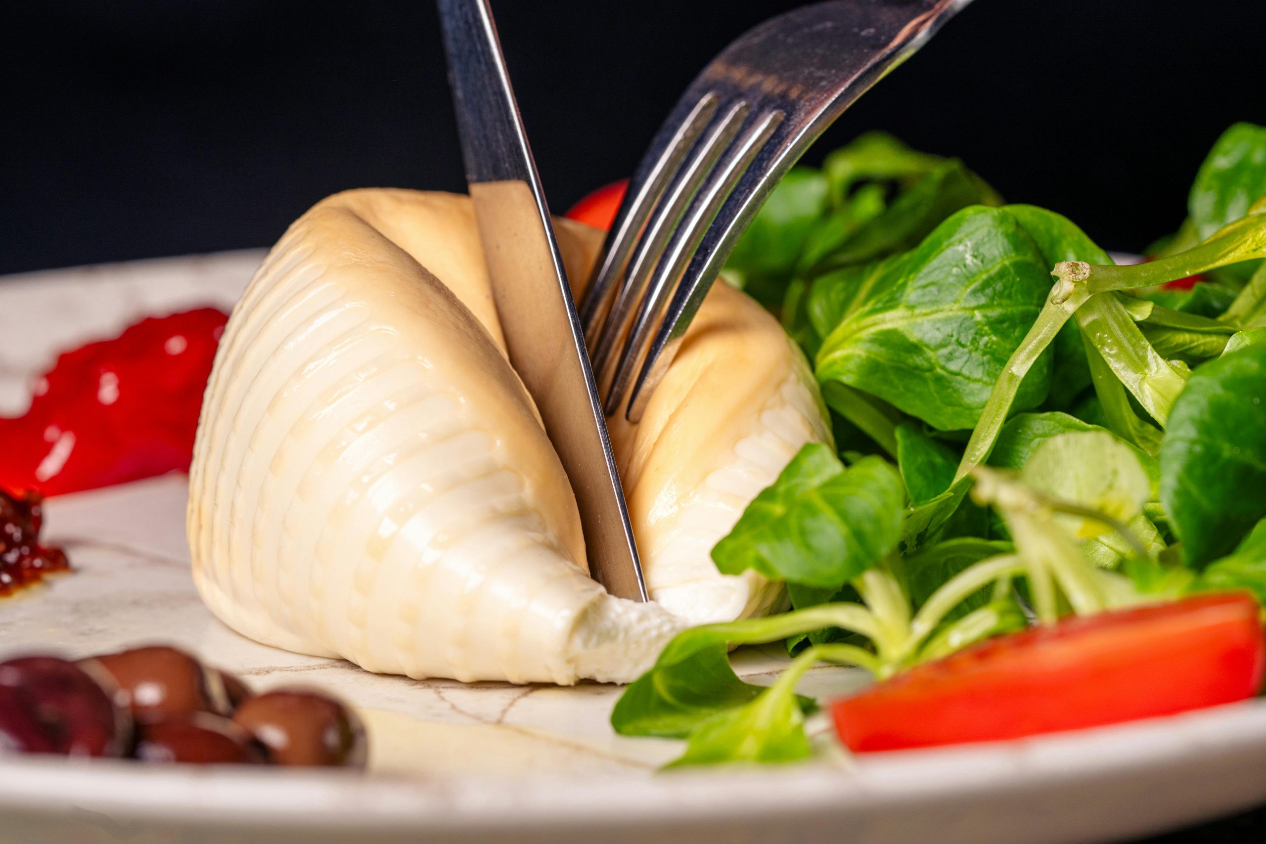 Fresh burrata cheese served with greens and vegetables.