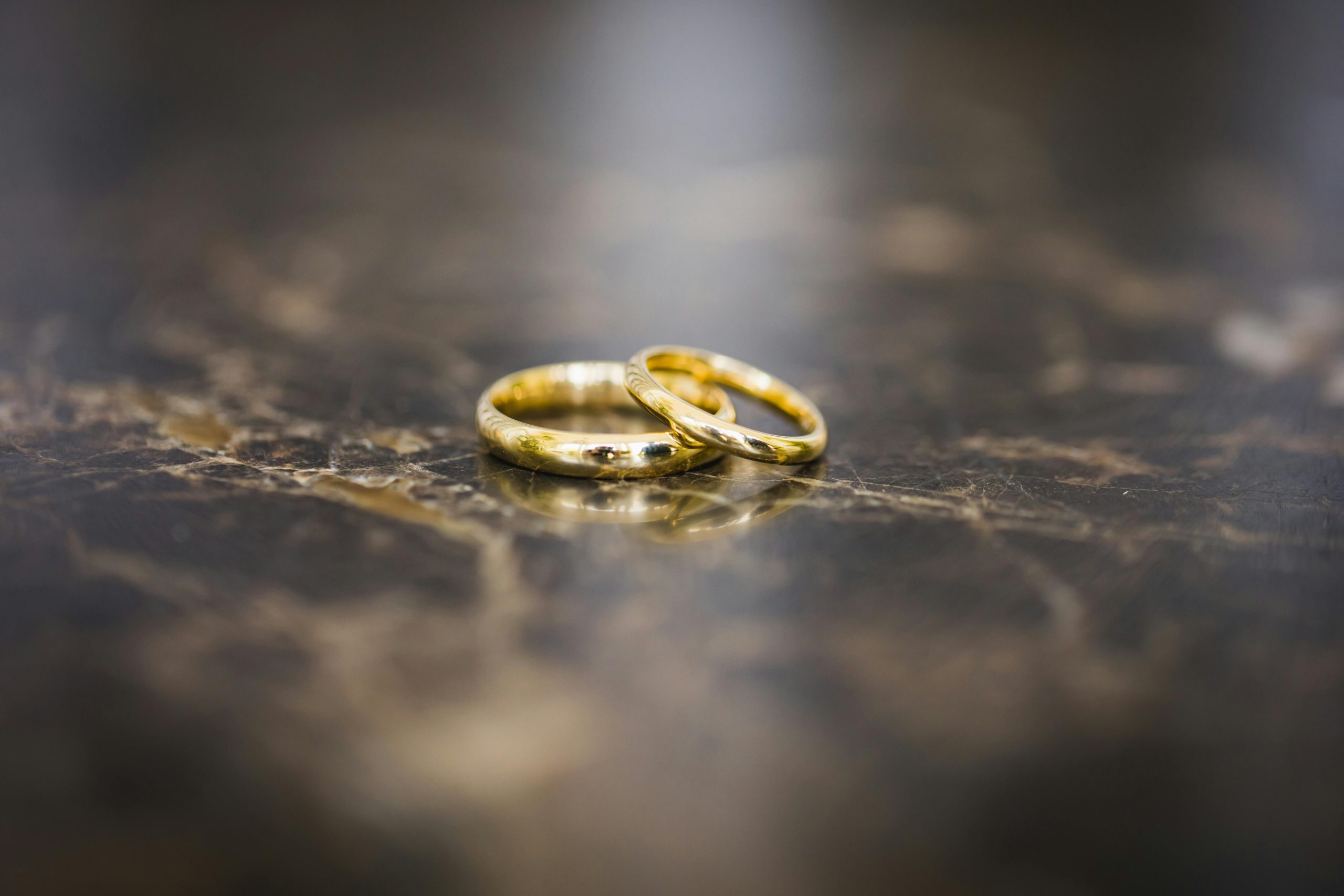 Close-up of elegant gold wedding rings on a polished marble surface, symbolizing marriage and love.