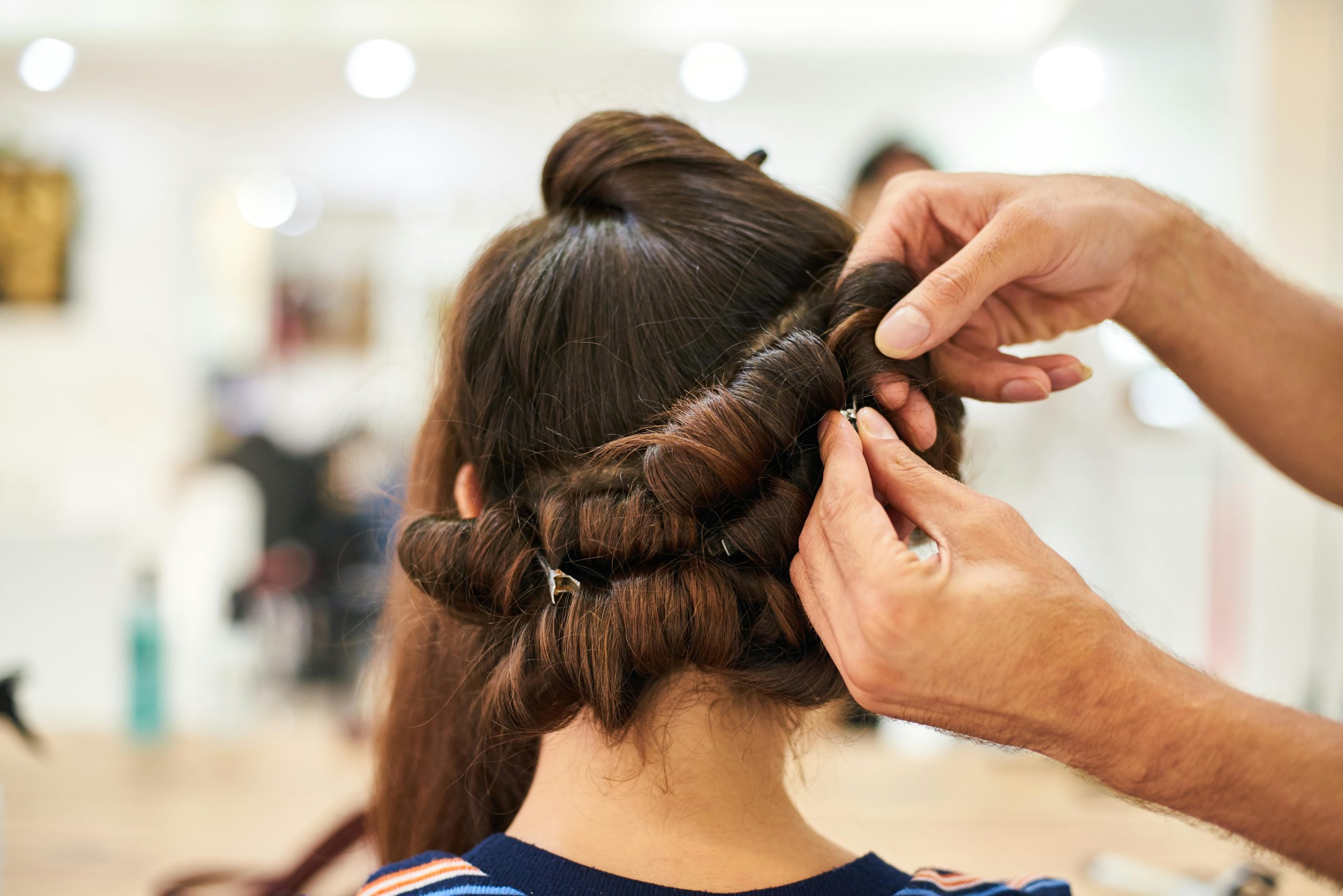 Close-up of a stylist crafting an intricate updo hairstyle in a modern salon.