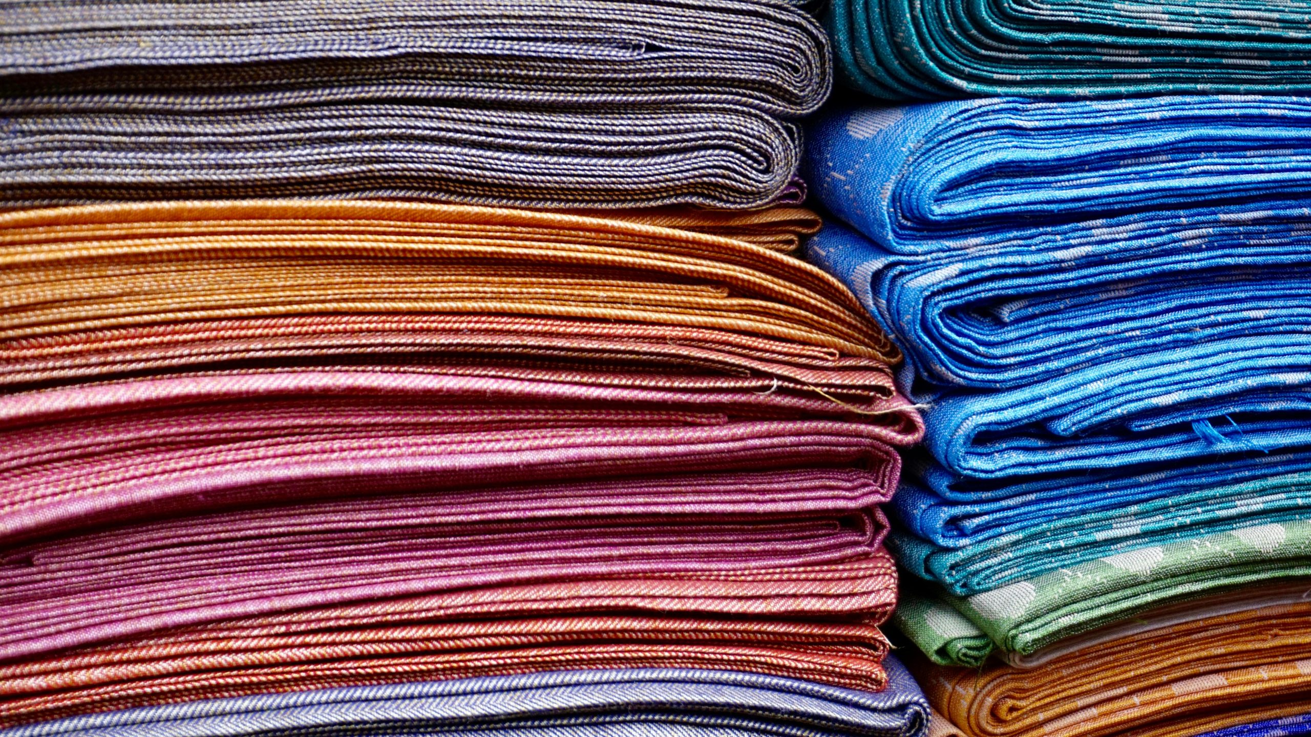 Vibrant and neatly stacked fabrics showcasing an array of colors and patterns, ideal for fashion and textile design.