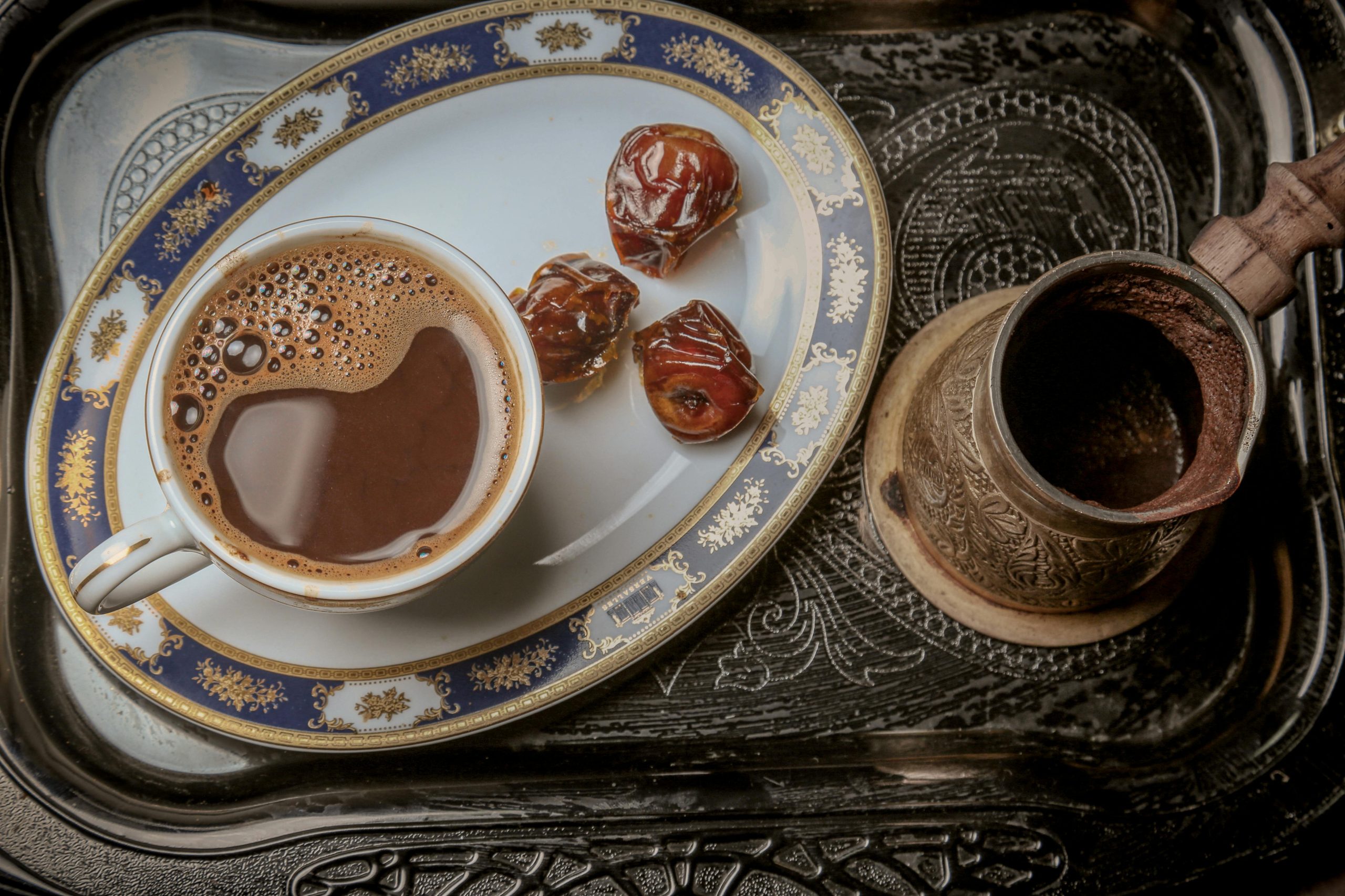 A close-up of traditional Turkish coffee with dates on an ornate serving tray for a cultural experience.