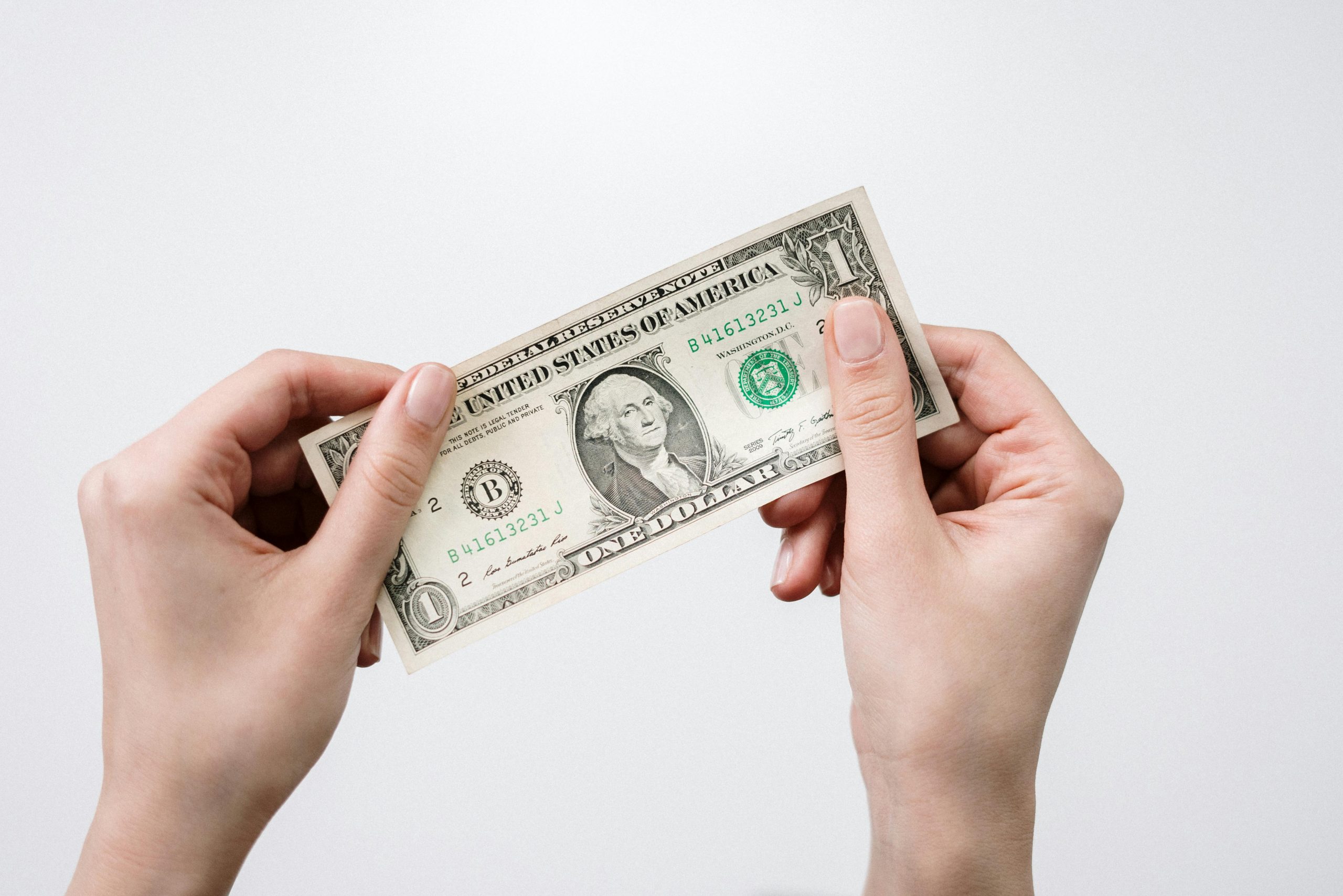 Hands holding a one dollar bill, depicting currency and finance closely.