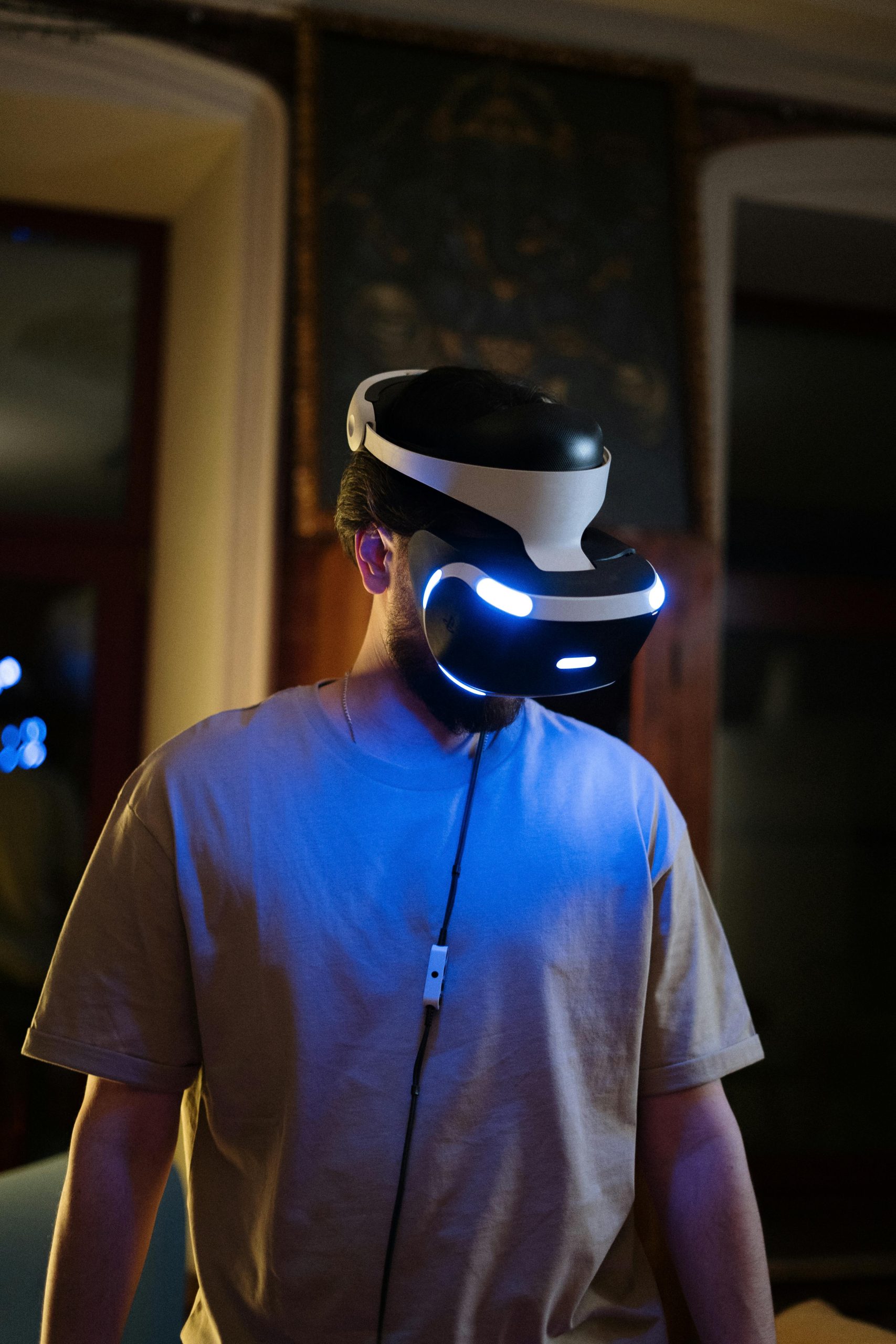 A young man using a VR headset in a dimly lit room indoors, showcasing virtual reality technology.