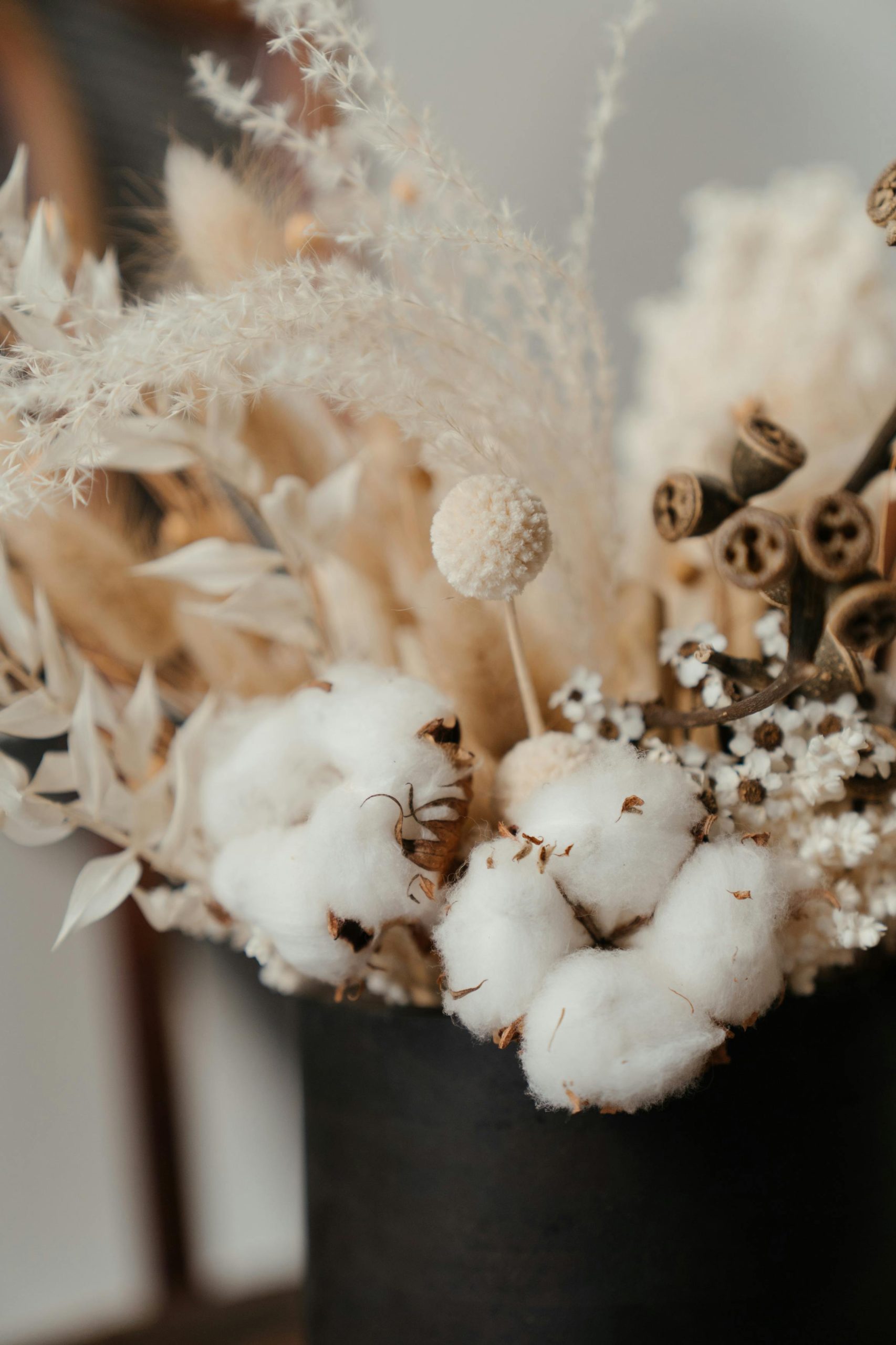 A beautiful arrangement featuring cotton with dried flowers in a rustic vase, showcasing a neutral palette.