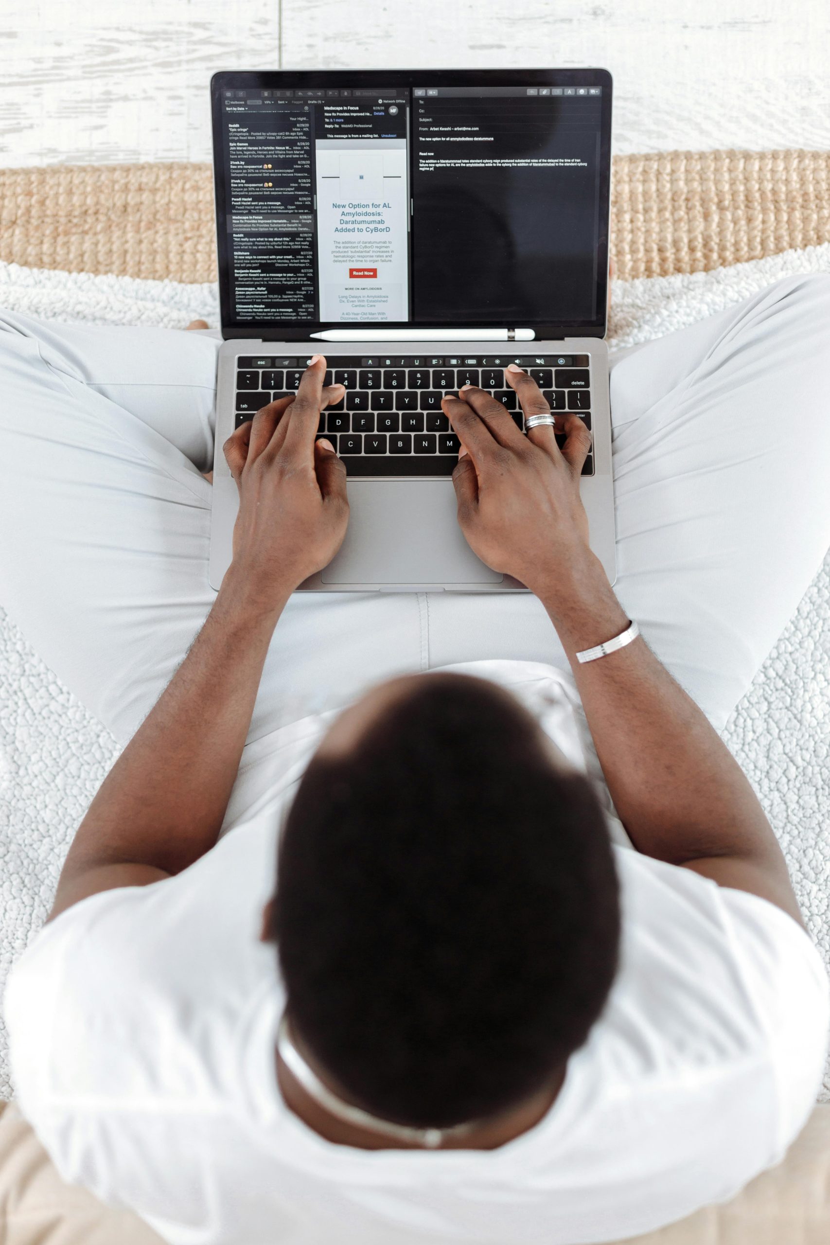 A man typing on a laptop at home, captured from above in a relaxed environment.