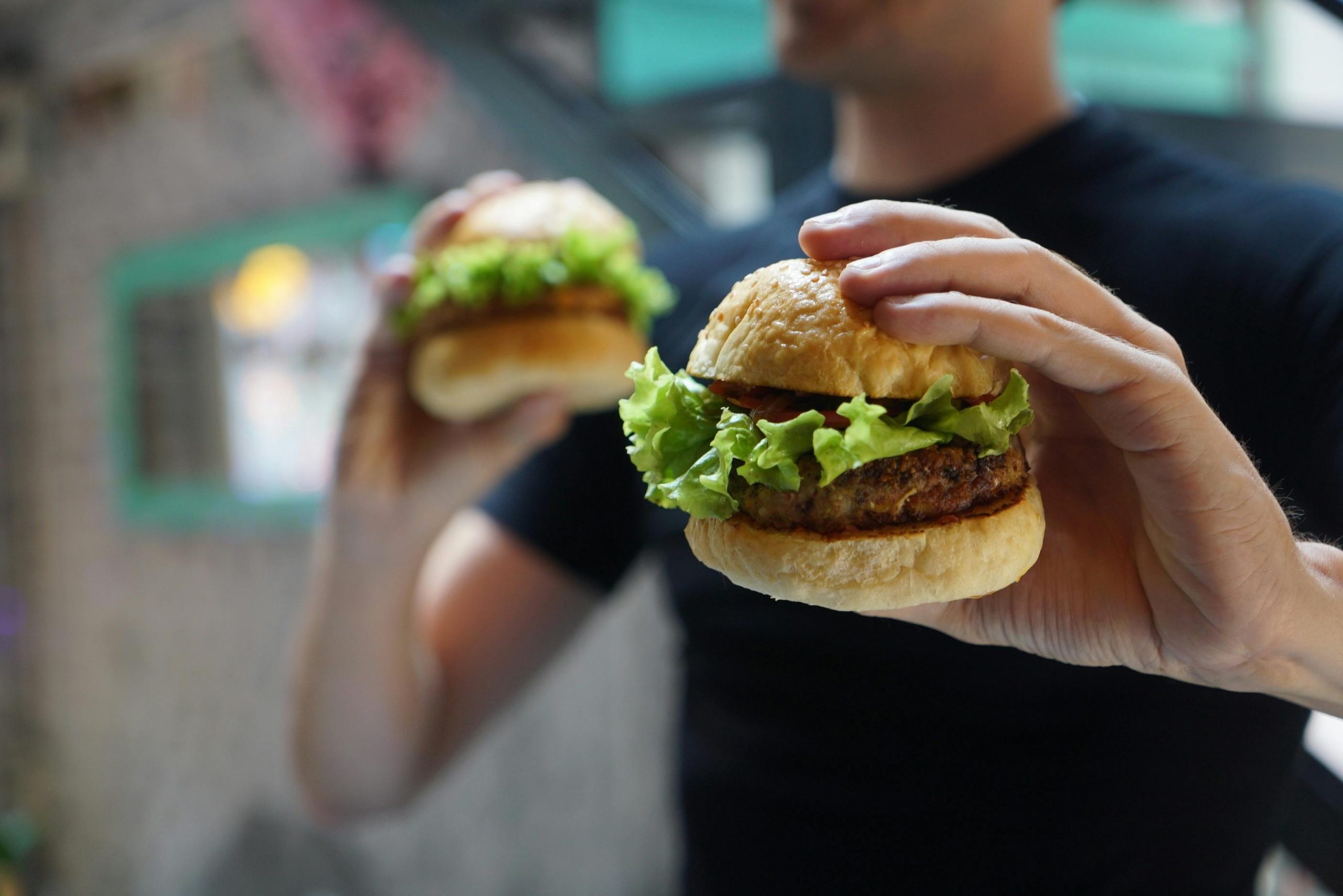 A close-up shot of a person holding a homemade burger with fresh lettuce, ideal for fast food themes.