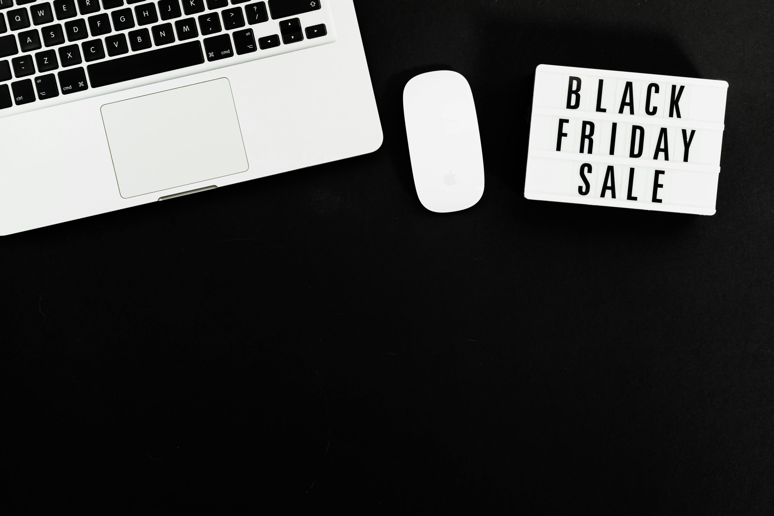 Black Friday sale sign with a laptop and mouse on a black background. Perfect for online shopping promotions.