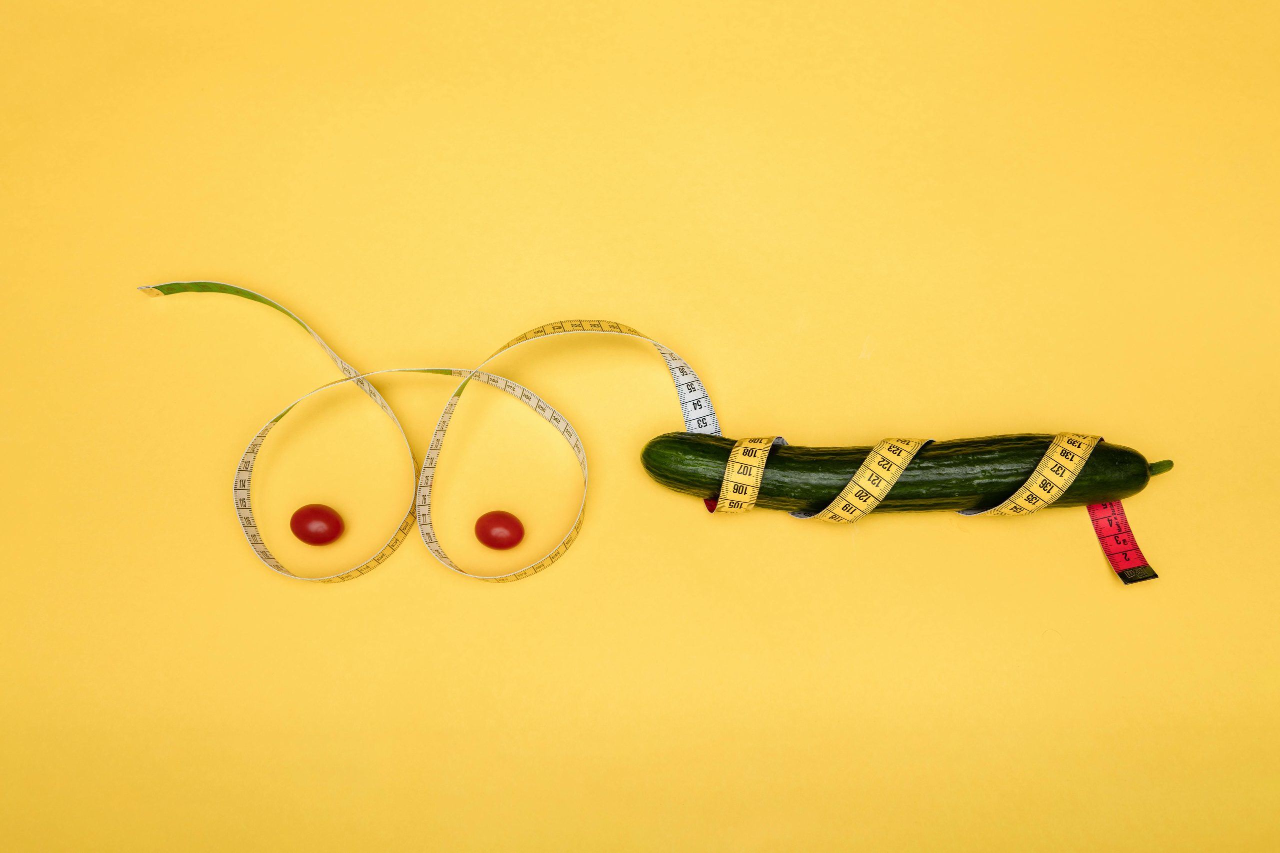 Playful composition with fruits and a tape measure on a yellow background.