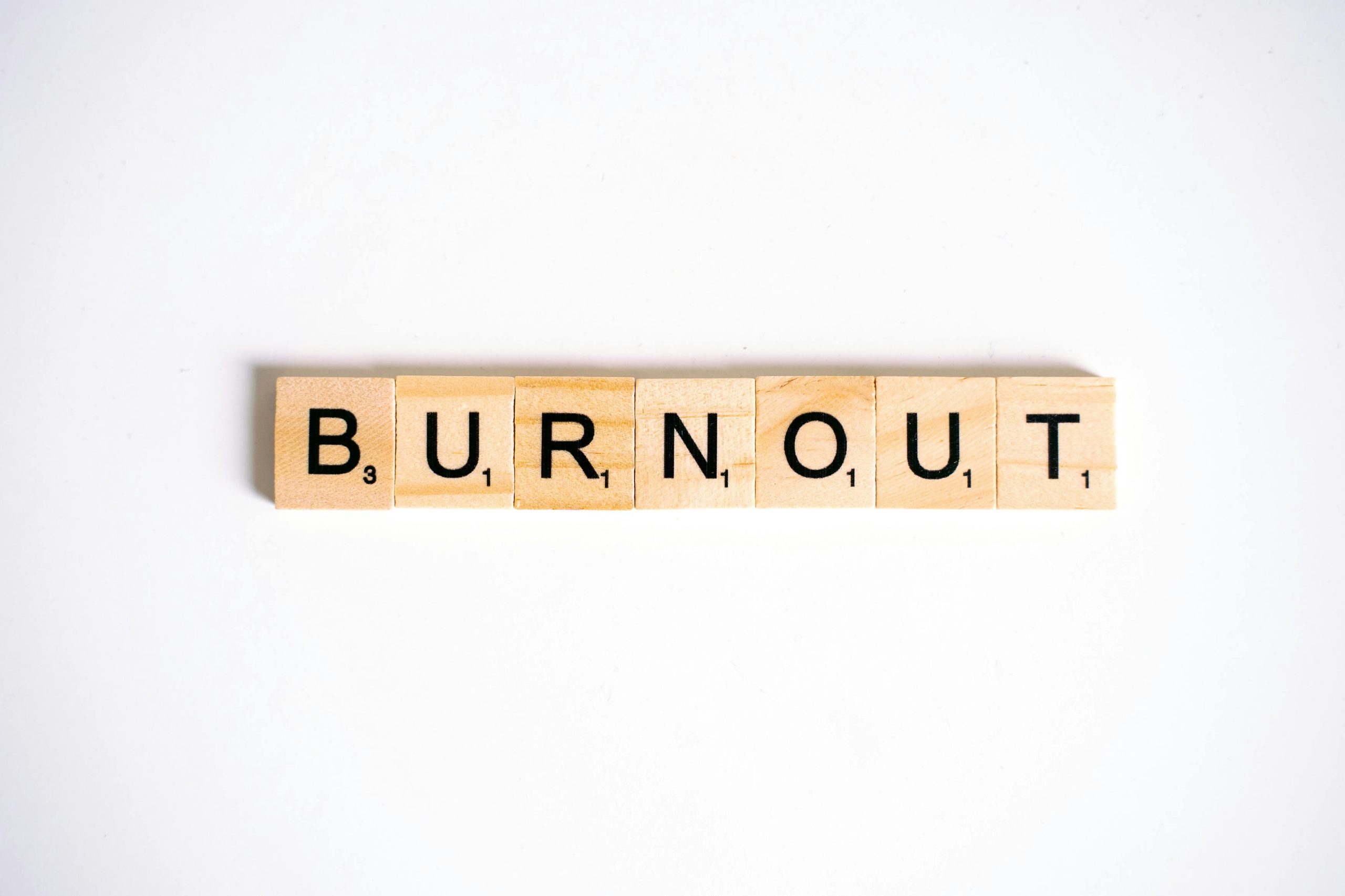 Conceptual image of 'Burnout' spelled with Scrabble tiles on a white background.