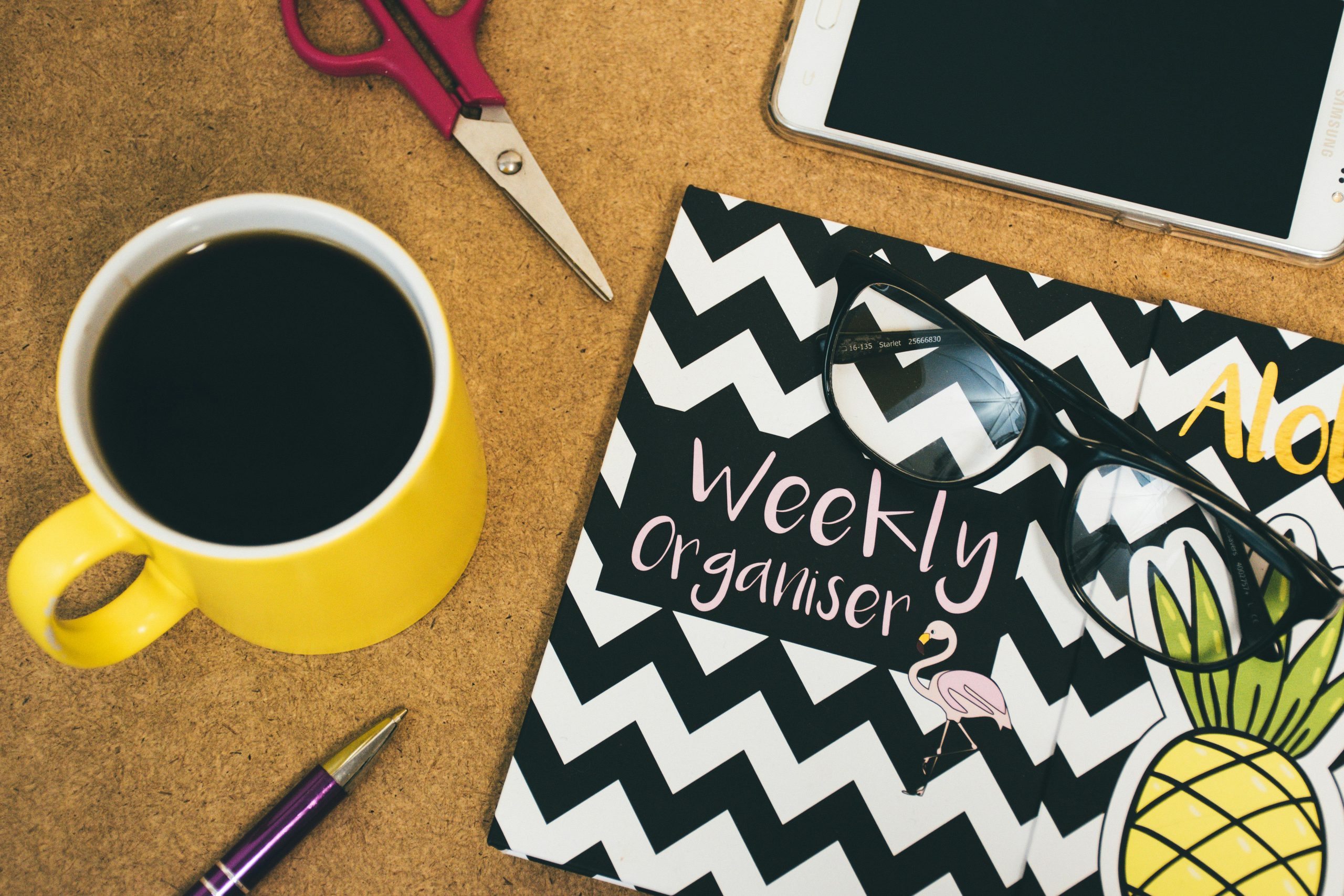 Flat lay of a workspace with coffee, notebook, smartphone, scissors, and pen for creativity.