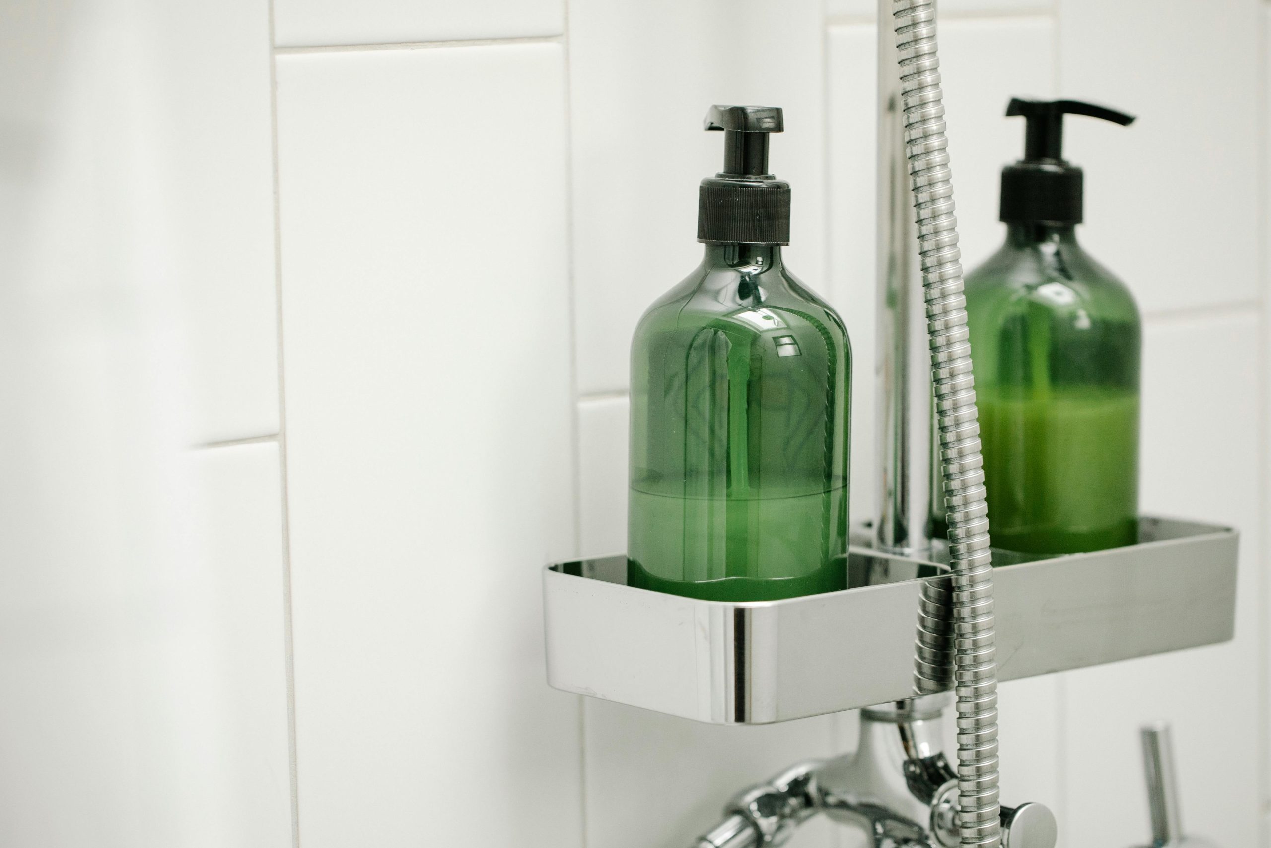 Green eco-friendly shower bottle in a modern bath setting. Clean and minimalist design.