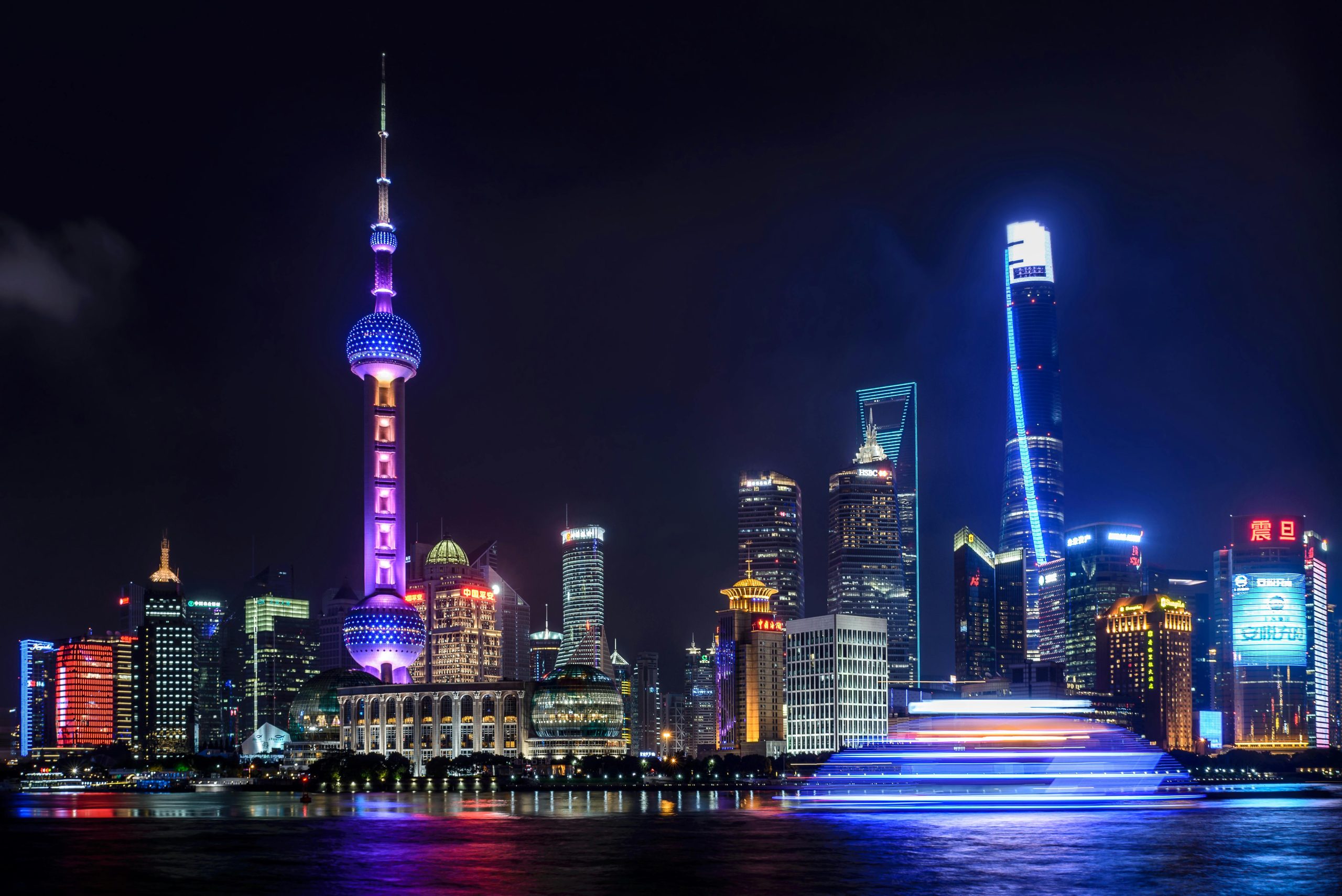 Stunning night view of Shanghai skyline with illuminated skyscrapers and the Oriental Pearl Tower reflecting in the water.