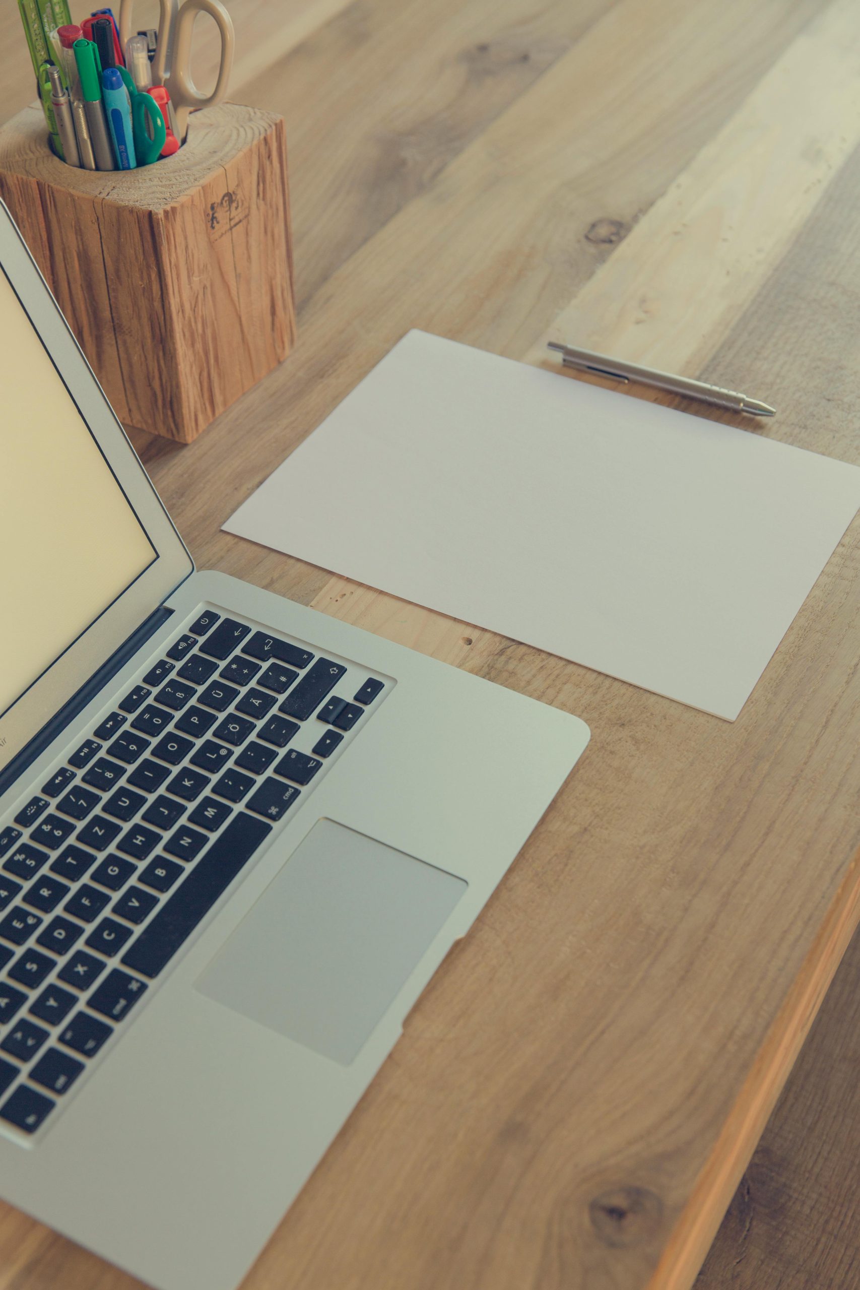 A minimalist wooden desk with laptop, papers, and stationery for productivity.