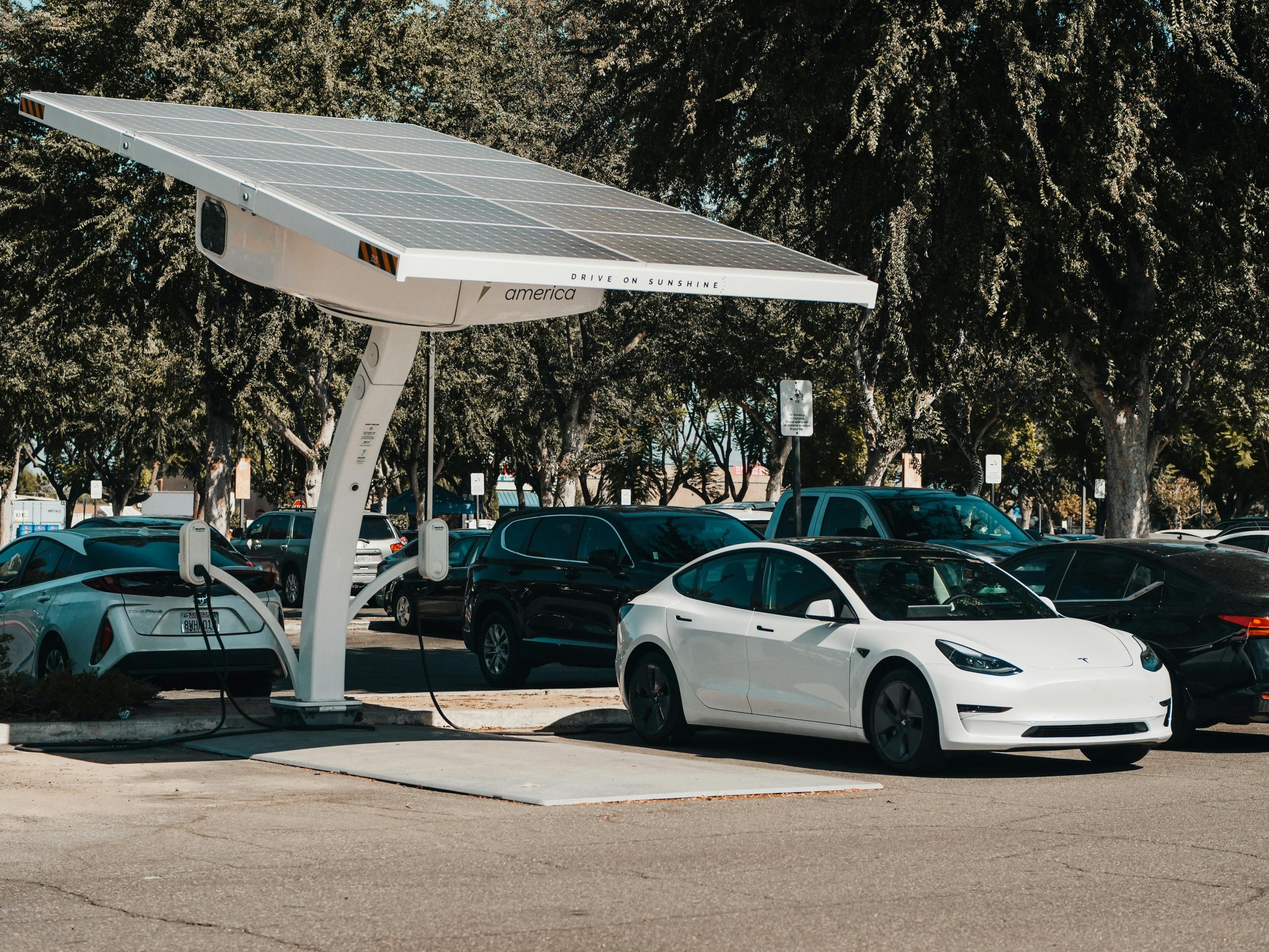 Electric car parked at a solar charging station outdoors, highlighting renewable energy and innovation.